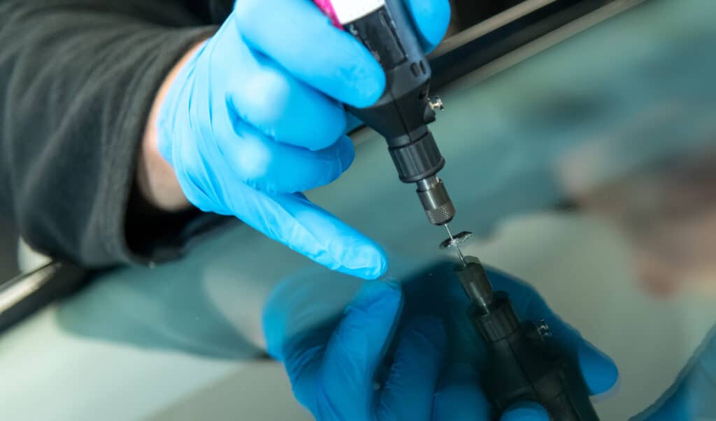 Technician repairing a chipped windshield using professional equipment.